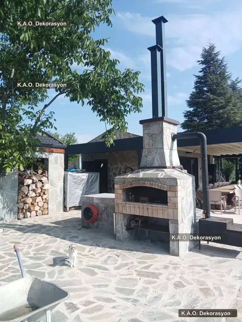 Bahçede taş kaplamalı, tuğla kemerli ağza ve bacaya sahip taş fırın
